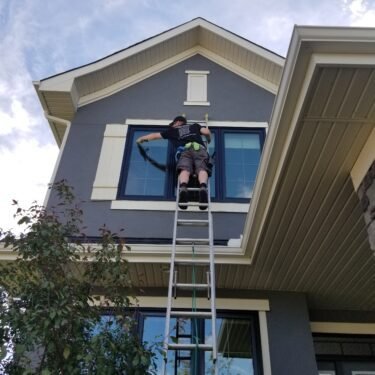 Man on ladder cleaning outside windows