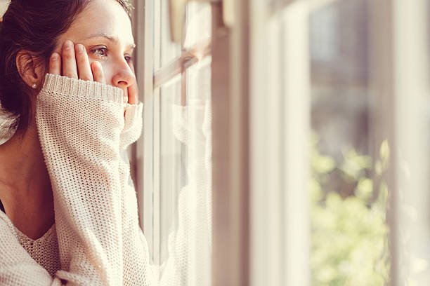 Woman looking out her clean windows after Filthy Masters came